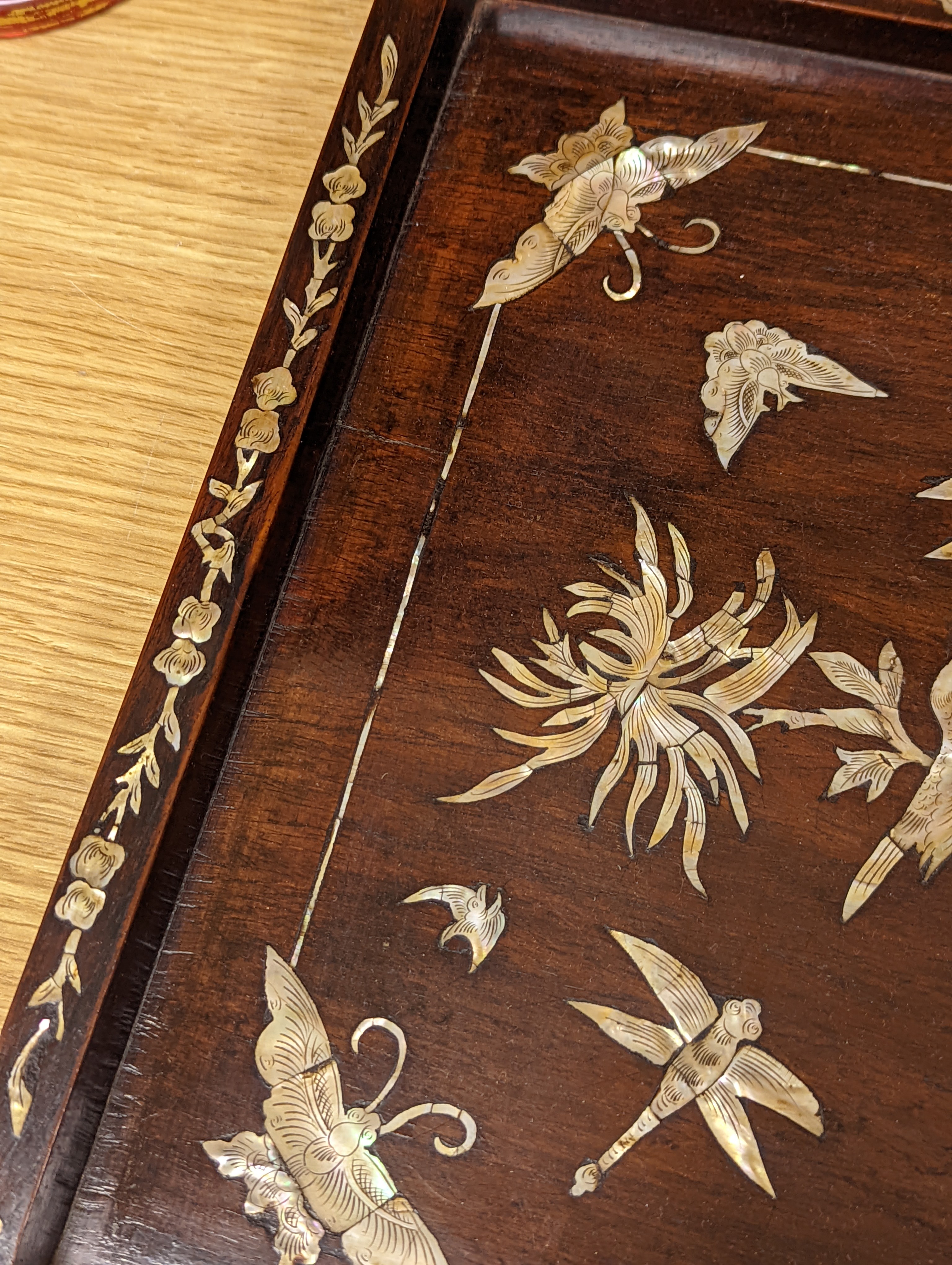 Two Chinese mother of pearl inlaid hongmu trays, the rectangular example with birds and insects amid flowers and the smaller oval example with a pavilion in a landscape within floral sprays 55x34cm